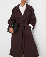 Gabardina oversize color marrón oscuro, con diseño cruzado, solapas grandes, mangas largas con trabilla en los puños, bolsillos delanteros y cinturón ajustable del mismo tejido.