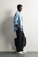 Pantalón negro confeccionado en mezcla de algodón, con cintura elástica, bolsillos frontales y cierre con cremallera y botón.
