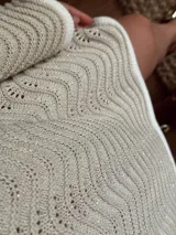 Vestido corto de tejido calado con patrón de ondas, confeccionado en algodón y lurex. Presenta mangas largas, cuello redondo y diseño holgado.