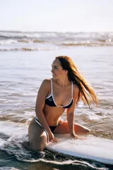 Conjunto de bikini negro con ribetes blancos. El corpiño es de corte triangular y la bombacha es tipo colaless.