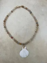 Collar largo de cuentas de piedras semipreciosas en tonos tierra, con dijes de conchas marinas.