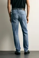 Jeans slim fit de color negro para hombre, con tiro medio, diseño de cinco bolsillos y cierre frontal con cremallera y botón.