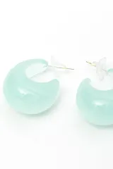 Aros tipo argolla gruesa y abombada, de color blanco y acabado brillante.