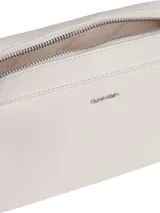Bolso tipo cámara (camera bag) de Calvin Klein, color blanco, con cuerpo rectangular y esquinas redondeadas. Presenta un logo metálico plateado en el frente y una correa ancha de tela tejida con el nombre de la marca repetido.