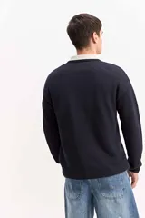 Sweater de punto texturizado color azul marino, de manga larga, con cuello polo en color beige contrastante.