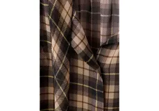 Blusa de poliéster con estampado a cuadros en tonos marrones y negros, con cuello camisero, manga larga y detalle de volados en la parte delantera.