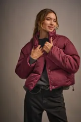 Campera puffer corta color borgoña, de corte holgado y cuello alto con cierre y snaps escondidos.