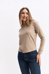 Remera de manga larga en color beige, con cuello redondo y corte recto, confeccionada en algodón.