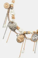 Collar metálico de diseño maximalista compuesto por perlas blancas de diversos tamaños, cuentas doradas y plateadas. Presenta múltiples colgantes que incluyen un camafeo dorado, un corazón plateado con grabados florales, medallas circulares y detalles de cadenas finas. Posee cierre de mosquetón.