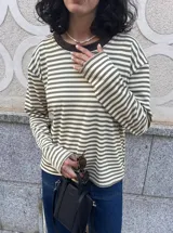 Remera de manga larga a rayas horizontales color verde y beige, con cuello redondo marrón en contraste y aberturas laterales.