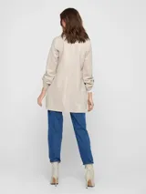 Abrigo largo color beige, tipo blazer, con solapa clásica y bolsillos laterales.