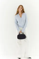 Sweater de punto fino color celeste claro, con cuello polo y tapeta de botones. Presenta hombros ligeramente caídos y remates acanalados en puños y bajo.