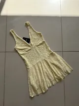 Vestido corto de encaje floral color amarillo pálido, con escote en V y breteles anchos.