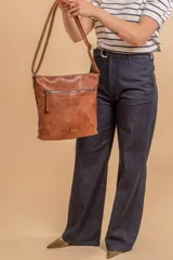 Bandolera mediana de cuero sintético color negro, con correa regulable, bolsillo frontal con cierre y compartimento principal.