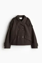 Campera corta cruzada color marrón oscuro, estilo gabardina, con cuello solapa ancho, doble botonadura frontal y bolsillos con solapa. Presenta charreteras en los hombros y puños anchos ajustables con botón.