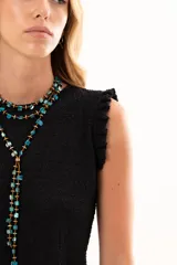 Blusa negra sin mangas con textura arrugada, cuello redondo y detalle de volados en los hombros. Presenta un corte asimétrico en el ruedo.