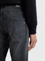 Jean de corte regular fit en color gris oscuro con efecto lavado, confeccionado en denim de alta calidad con cierre de botón y cremallera.