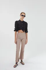 Pantalón de cuero color beige, de corte recto, tiro medio y tajos en el ruedo.