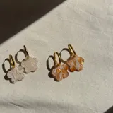 Aros de argolla dorada en acero quirúrgico con dije de flor en acrílico con efecto marmolado.