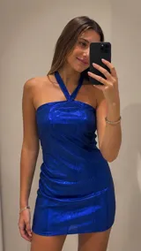 Vestido corto al cuerpo de tela metalizada en color azul eléctrico, con escote halter y diseño sin mangas.