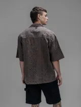 Camisa clásica de manga corta, color chocolate con efecto desgaste, confeccionada en algodón bordado (broderie) con diseño floral calado. Presenta cuello abierto y calce oversize.