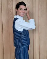 Chaleco de corte recto y largo a la cintura, confeccionado en denim con estampado de rayas verticales en tonos azul y blanco. Presenta cuello redondo y costuras visibles que definen su estructura.