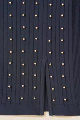 Sweater de punto fino en color negro, con diseño de canalé, cuello redondo y mangas largas. Presenta un corte ajustado con aberturas laterales en el ruedo y está decorado con pequeñas cuentas doradas en la parte frontal.