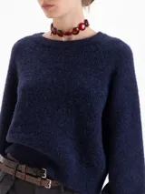 Sweater de tejido de punto color verde, con cuello redondo, mangas largas con hombros caídos y puños acanalados. Presenta un diseño de textura sutil en el frente.