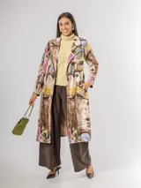 Trench de diseño urbano con acabado agamuzado, de corte recto y largo midi. Presenta un estampado abstracto multicolor con tonos rojizos, azules y ocres, cuello solapa, mangas largas y cinturón ajustable en la cintura.