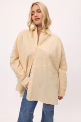 Camisa oversize a rayas verticales rosas y blancas, con cuello clásico, cierre frontal con botones y mangas largas.