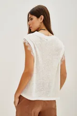 Musculosa blanca de lino con cuello redondo y detalle de encaje en las mangas.
