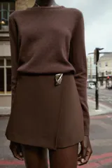 Falda pantalón corta de tiro alto con estampado animal print, cierre lateral oculto y aplique metálico triangular en la parte delantera.