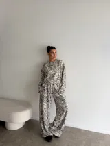 Conjunto de dos piezas compuesto por una remera de manga larga y un pantalón de corte ancho, ambos confeccionados en tela de viscosa con estampado animal print tipo cebra en tonos beige y negro.