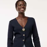 Cárdigan azul marino de punto canalé, con escote en V, cierre frontal con botones dorados y mangas largas.