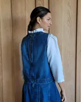Chaleco de corte recto y largo a la cintura, confeccionado en denim con estampado de rayas verticales en tonos azul y blanco. Presenta cuello redondo y costuras visibles que definen su estructura.