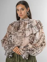 Camisa de seda italiana con diseño reversible, permitiendo usar el lazo en la parte frontal o posterior. Presenta un estampado sutil con motivos abstractos y animal print, cuello alto con volados, mangas largas con puños elásticos y corte holgado.