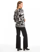 Blusa de seda fría con estampado floral en blanco y negro. Presenta cuello a la base, mangas tres cuartos amplias y ruedo con abertura lateral decorada con botones.