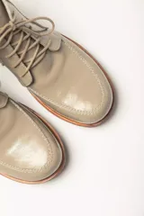 Bota acordonada de cuero vacuno con acabado charol color suela, con suela de goma tipo crepe y costuras reforzadas.