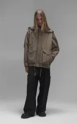 Campera técnica liviana color beige, confeccionada en microfibra de alta densidad con acabado mate. Presenta mangas desmontables que permiten convertirla en chaleco, cuello tipo camisa, cierre frontal oculto bajo cartera y logo bordado en el pecho. Incluye cuatro bolsillos frontales de gran tamaño con solapa y puños con elástico.