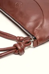 Cartera bandolera de cuero marrón con forma relajada, diseño de costuras curvas y detalles de nudos hechos a mano en las asas.