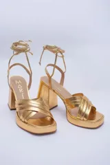 Sandalias doradas de cuero con plataforma y tiras para atar al tobillo.