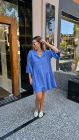 Vestido corto de manga larga con volados, color lavanda, con cuello camisero y botones frontales.