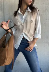 Chaleco de punto acanalado en color natural, con escote en V, cierre frontal con botones y detalles de flores bordadas en el frente.