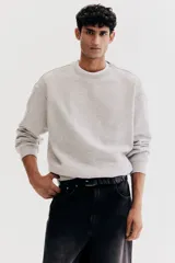 Buzo gris claro de corte holgado, con cuello redondo y mangas largas.