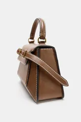 Bolso de mano tipo city color marrón, con diseño estructurado, costuras a la vista en color blanco y detalles de hebillas metálicas decorativas en la parte frontal. Cuenta con asa de mano superior, correa ajustable para usar como bandolera y cierre mediante solapa con imán.