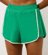 Bermuda deportiva tipo runner color verde, confeccionada en microfibra liviana. Presenta cintura elástica, short interno integrado para mayor seguridad y detalles de friso en color blanco en los bordes redondeados.