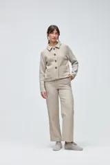 Campera corta con cuerpo de lana tejida en textura tweed y mangas de punto liso en color marrón. Presenta cuello camisero, cierre frontal con botones y bolsillos frontales tipo plaque.