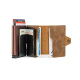 Billetera delgada de cuero sintético color marrón claro, con textura envejecida y costuras visibles. Presenta un mecanismo de eyección de tarjetas y un cierre a presión lateral.