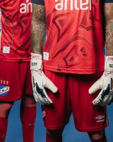 Short de arquero del Club Nacional de Football, temporada 2025. Diseño en color rojo con detalles en blanco y azul, confeccionado en tejido deportivo transpirable. Incluye el escudo del club bordado en la parte inferior.