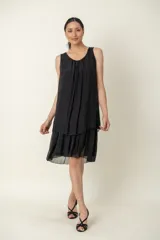 Vestido negro de seda, modelo suelto sin mangas, con escote redondo y volados en el bajo.